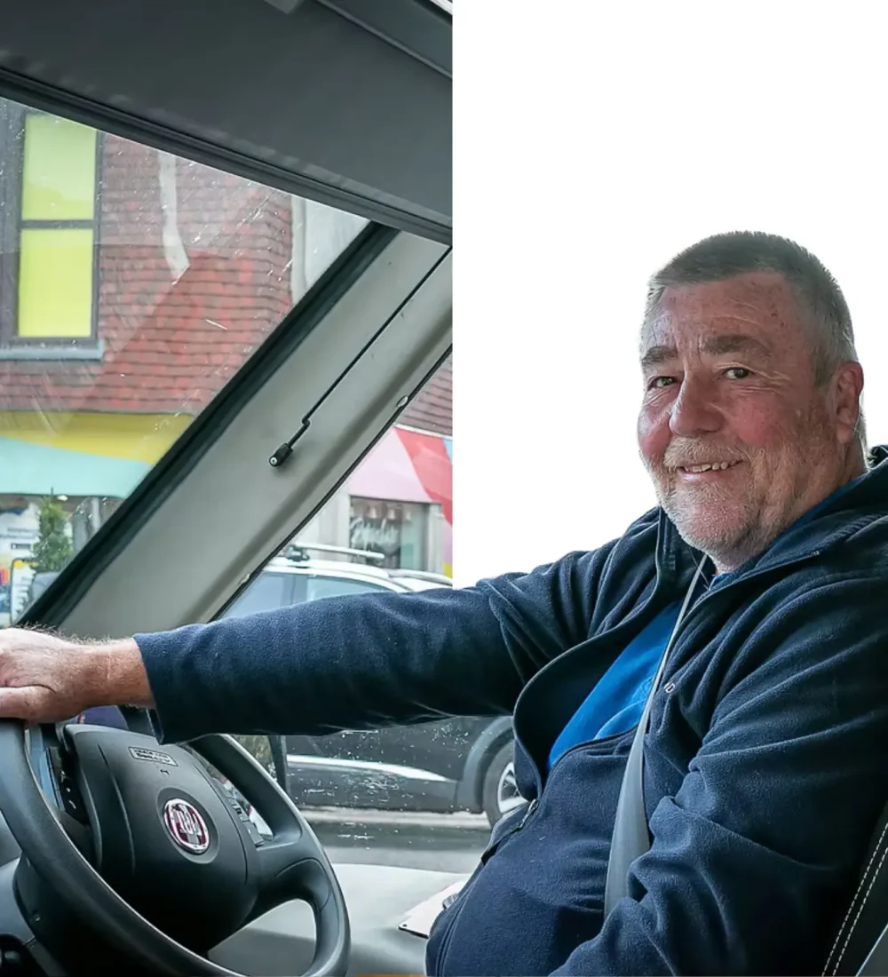 A smiling Wanderbus volunteer driver at the wheel of the minibus